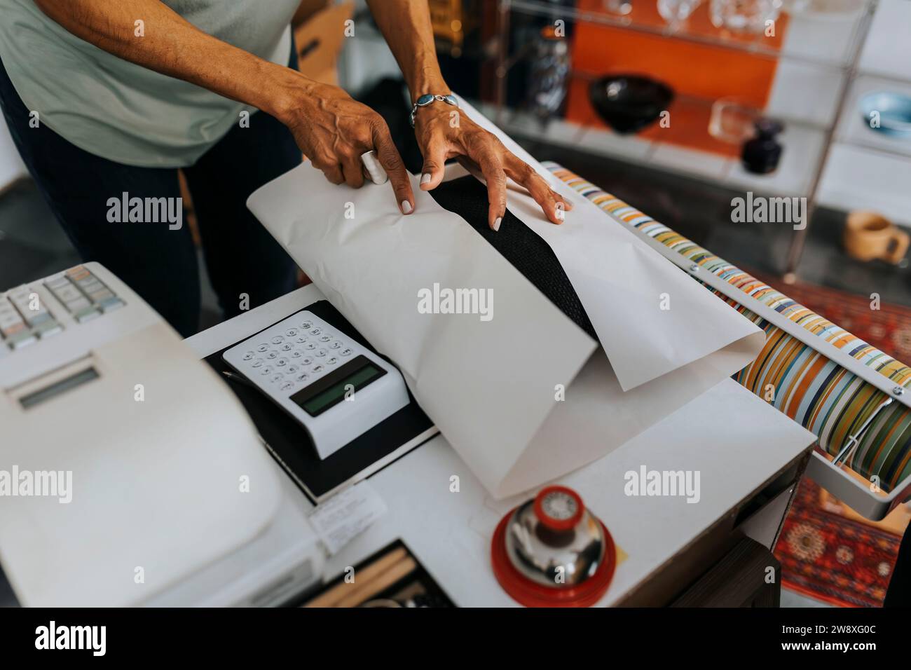 Midsection of saleswoman wrapping product at checkout in antique shop Stock Photo