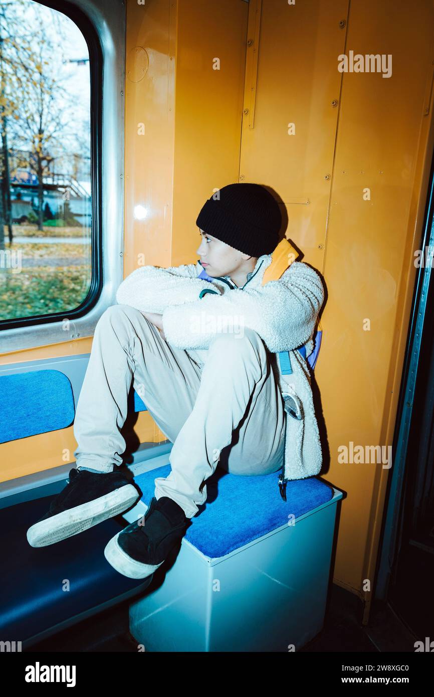 Contemplative boy looking through window while sitting in tram Stock Photo
