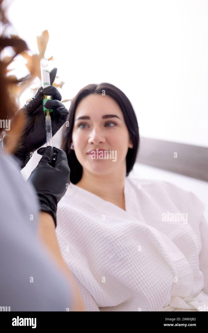 Careful young woman doctor holding injector performing mesotherapy of