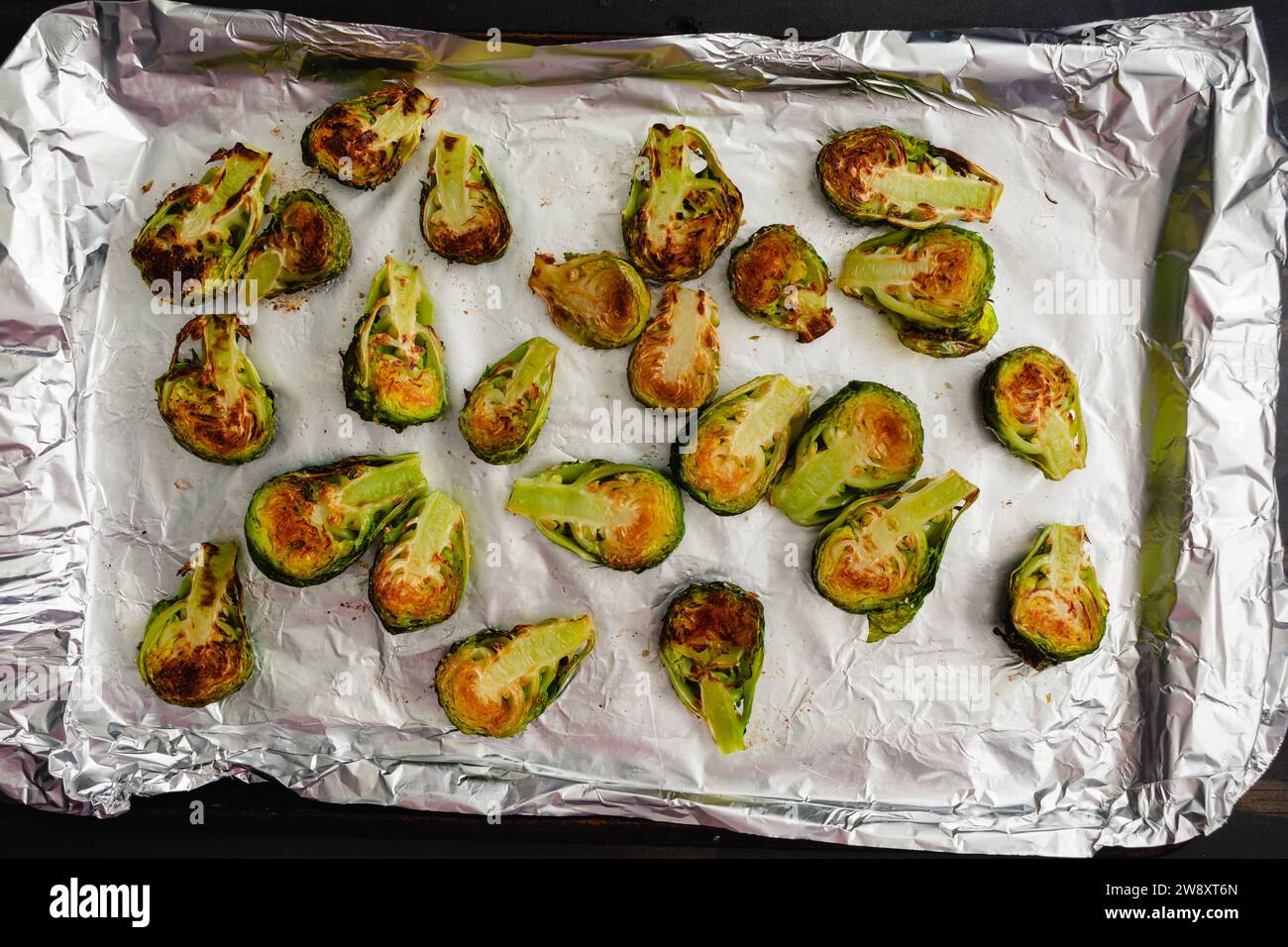 Roasted Brussels Sprout Haves on a Foil-Lined Sheet Pan: Browned baby cabbages on a cookie sheet covered with aluminum foil Stock Photo
