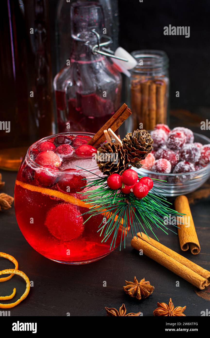 Spiced Cranberry Bourbon Old Fashioned with Sugared Cranberries: Red Christmas holiday-themed bourbon cocktail garnished with a mini evergreen branch Stock Photo