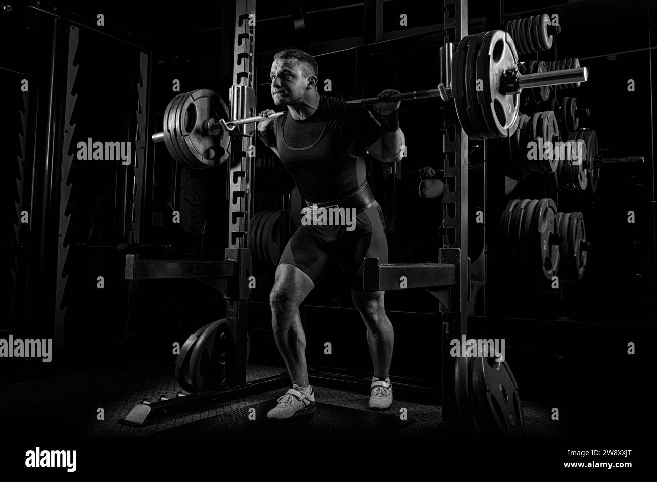 The weightlifter is preparing to lift a very heavy barbell. He exhales breathlessly and strains as much as possible before performing the exercise Stock Photo