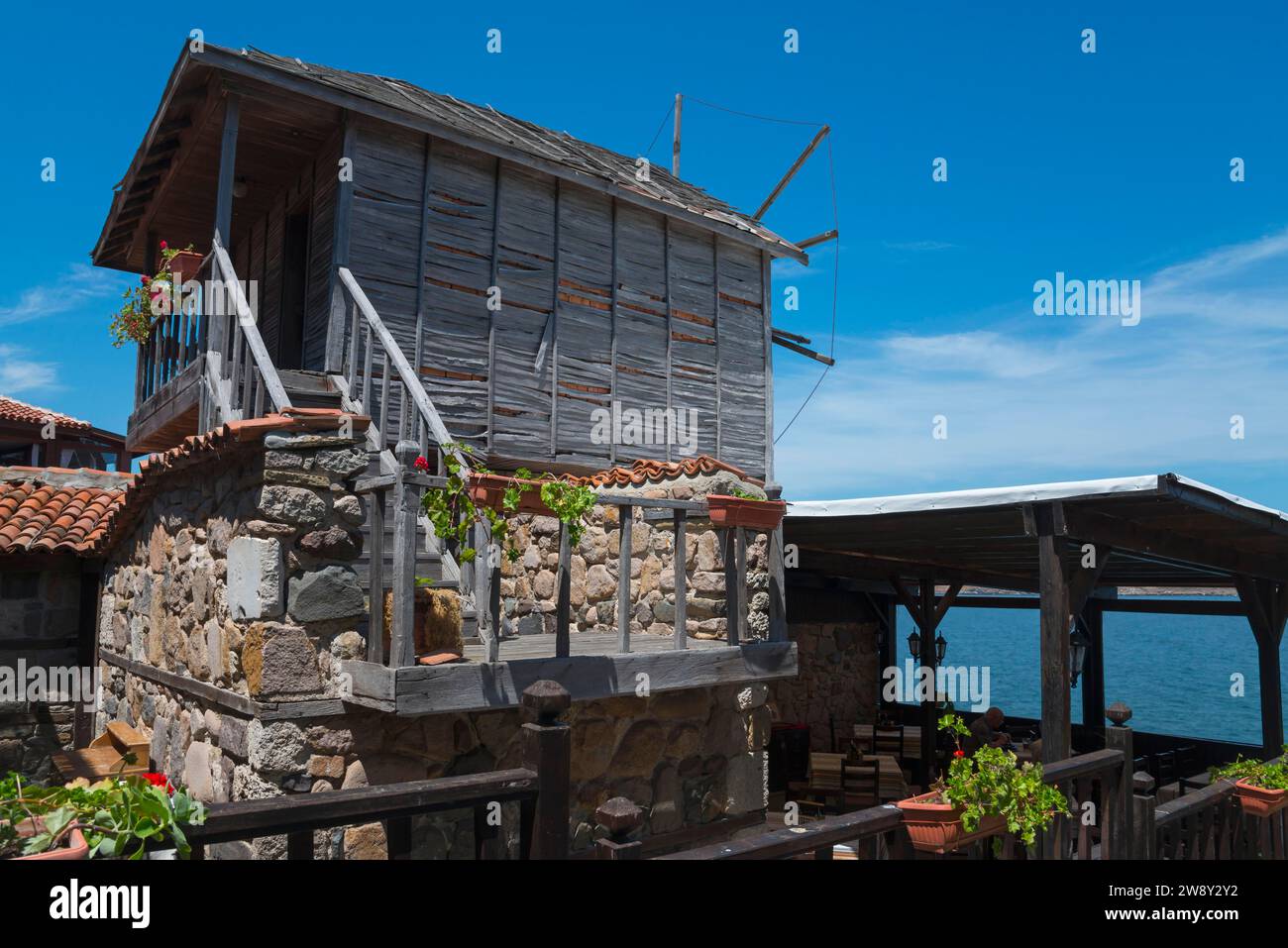 Rustic wooden windmill overlooking the sea, surrounded by plants under a blue sky, Restaurant The Windmill, Windmill, Old Town, Sosopol, Sozopol Stock Photo