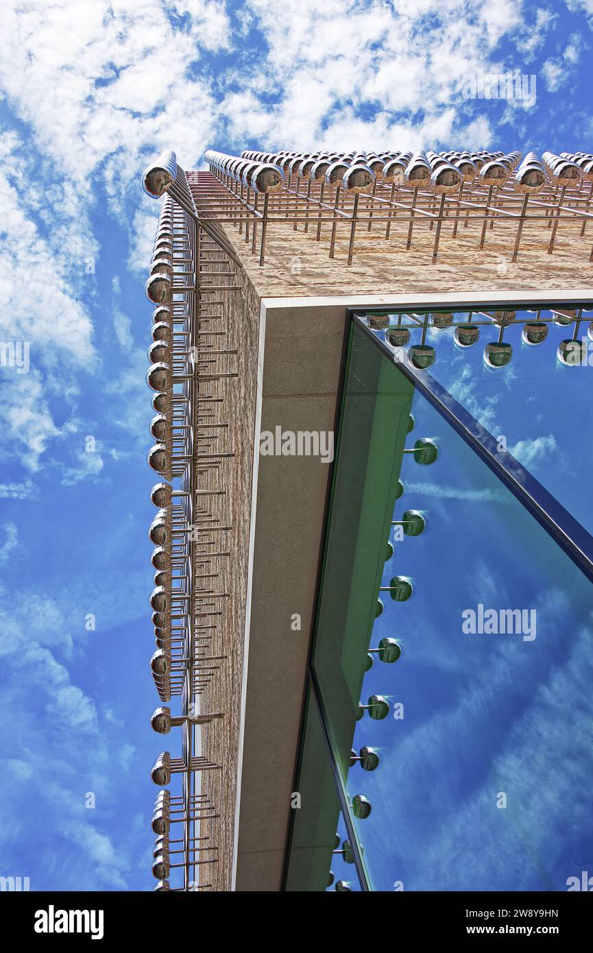 View from underneath of a modern building and the cloudy blue sky reflecting on the glass windows Stock Photo