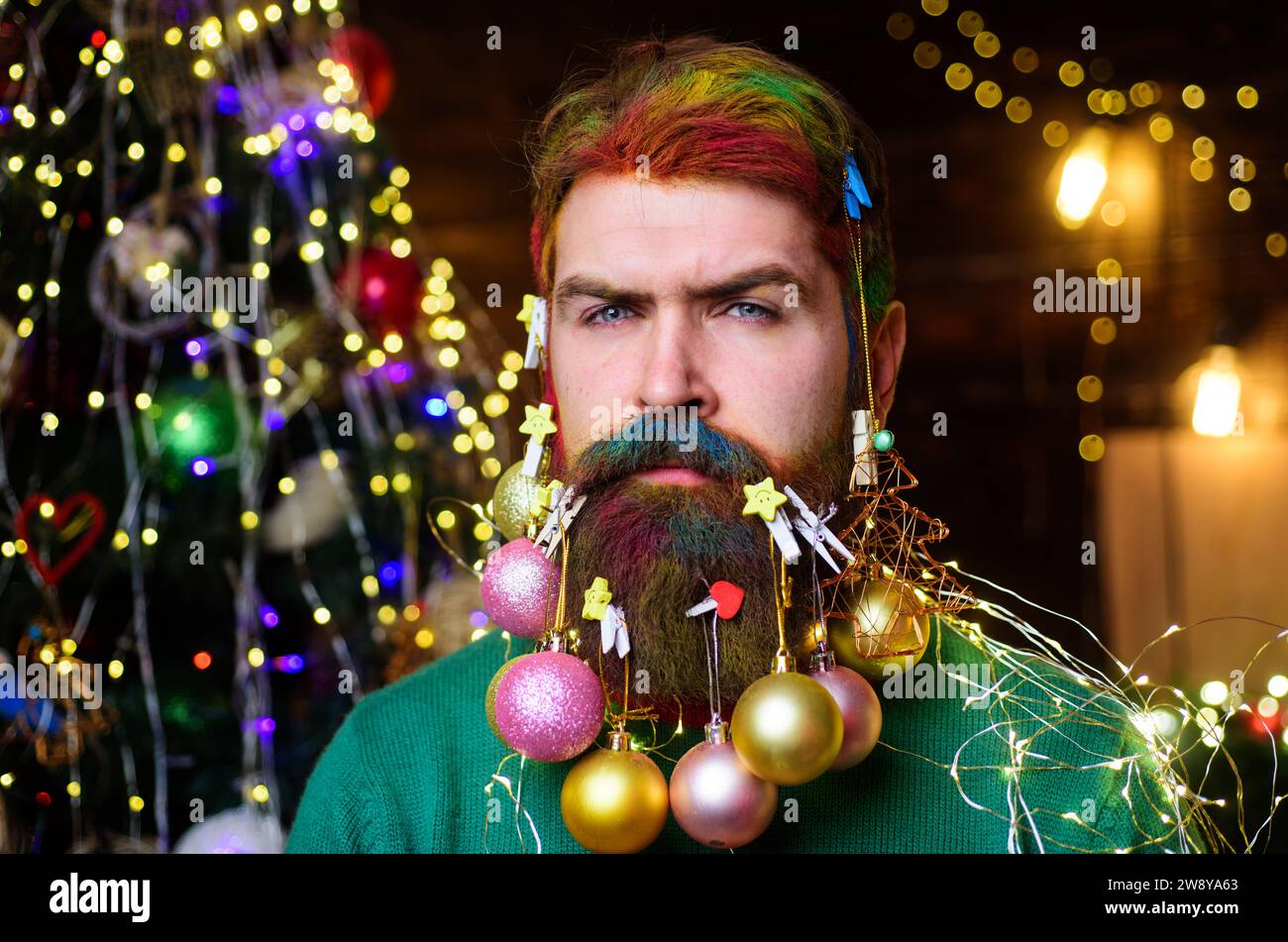 Merry Christmas and Happy New Year. Christmas barbershop. Serious man with colorful dyed hair and decorated beard for New Year party. Christmas beard Stock Photo