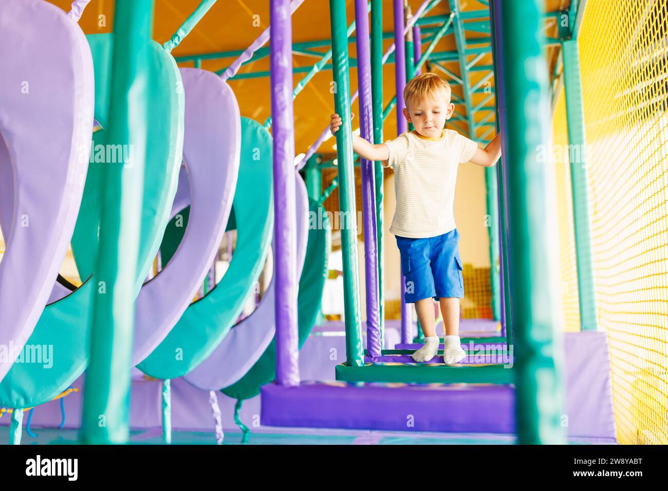 Cute little boy crawling and playing on colorful playground at amusement park Stock Photo