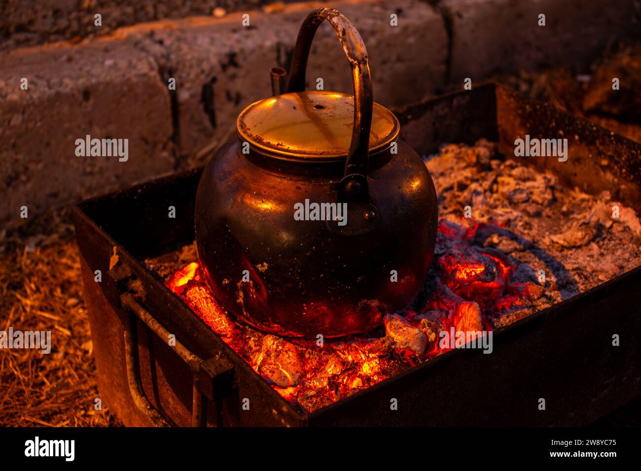 burning coals to boil water during camping and metal stove on picnic Stock Photo