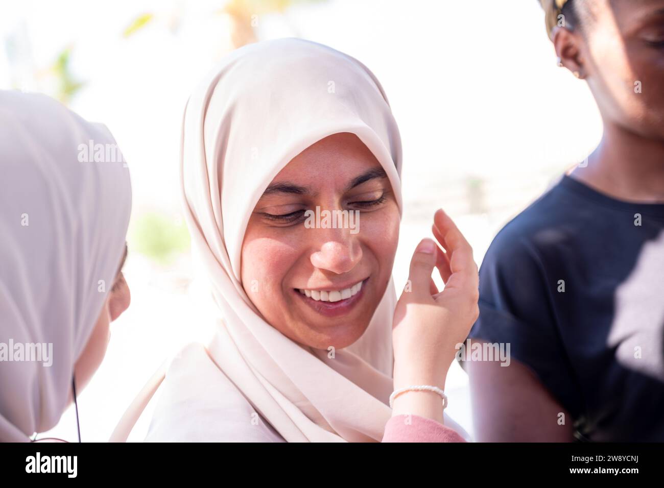 muslim female adjusting her hijab with a help  from other person Stock Photo