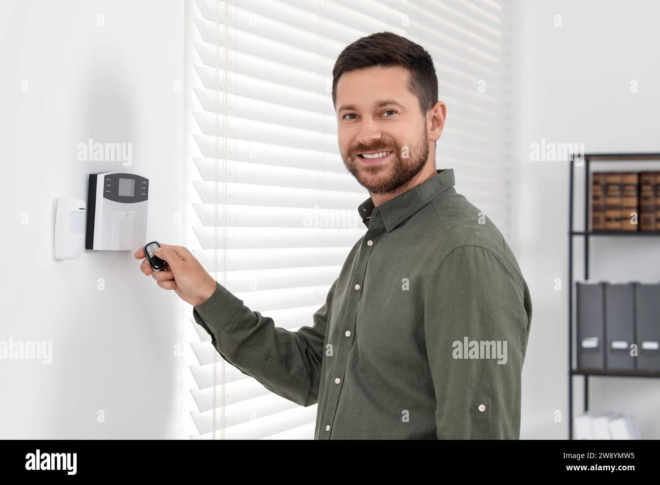 Home security system. Man using alarm key fob indoors Stock Photo