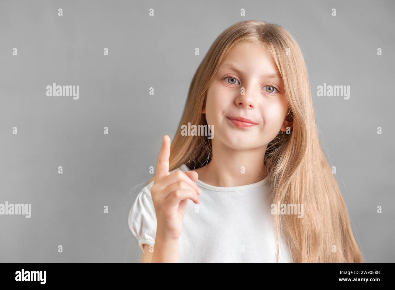 Portrait of cute little girl with long light hair, direct finger up