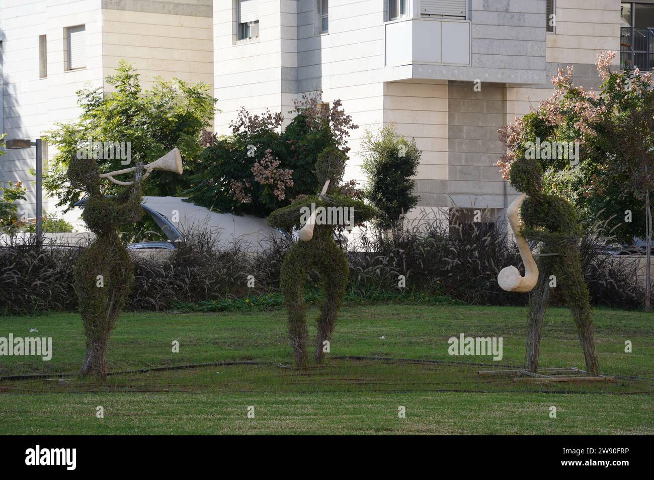 Topiary sculpture of musicians with with music instruments made of grass. Urban design, city architecture, park decoration. Stock Photo