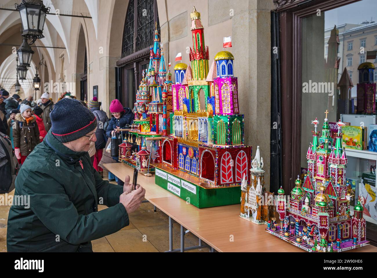 People taking photos of Szopki (Christmas Nativity scenes) at opening of annual contest in December, event included in UNESCO Cultural Heritage list, at arcades of Sukiennice (Cloth Hall), Main Market Square, Kraków, Poland Stock Photo