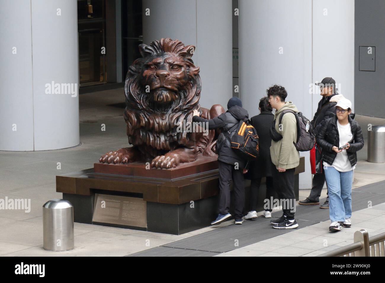 Tourists rub (for Good Luck) a lion statue named 'Stitt' at the entrance to HSBC Headquarters, Central, Hong Kong, China Stock Photo