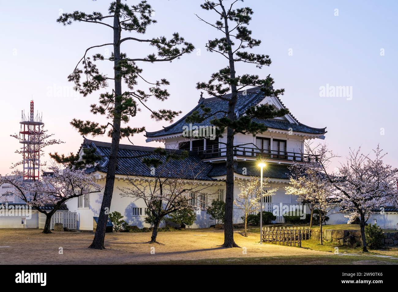 Fukuyama castle in Japan. Dawn view of the restored Tsukimi yagura, turret, with its moon-viewing balcony, while in front, cherry blossom trees. Stock Photo