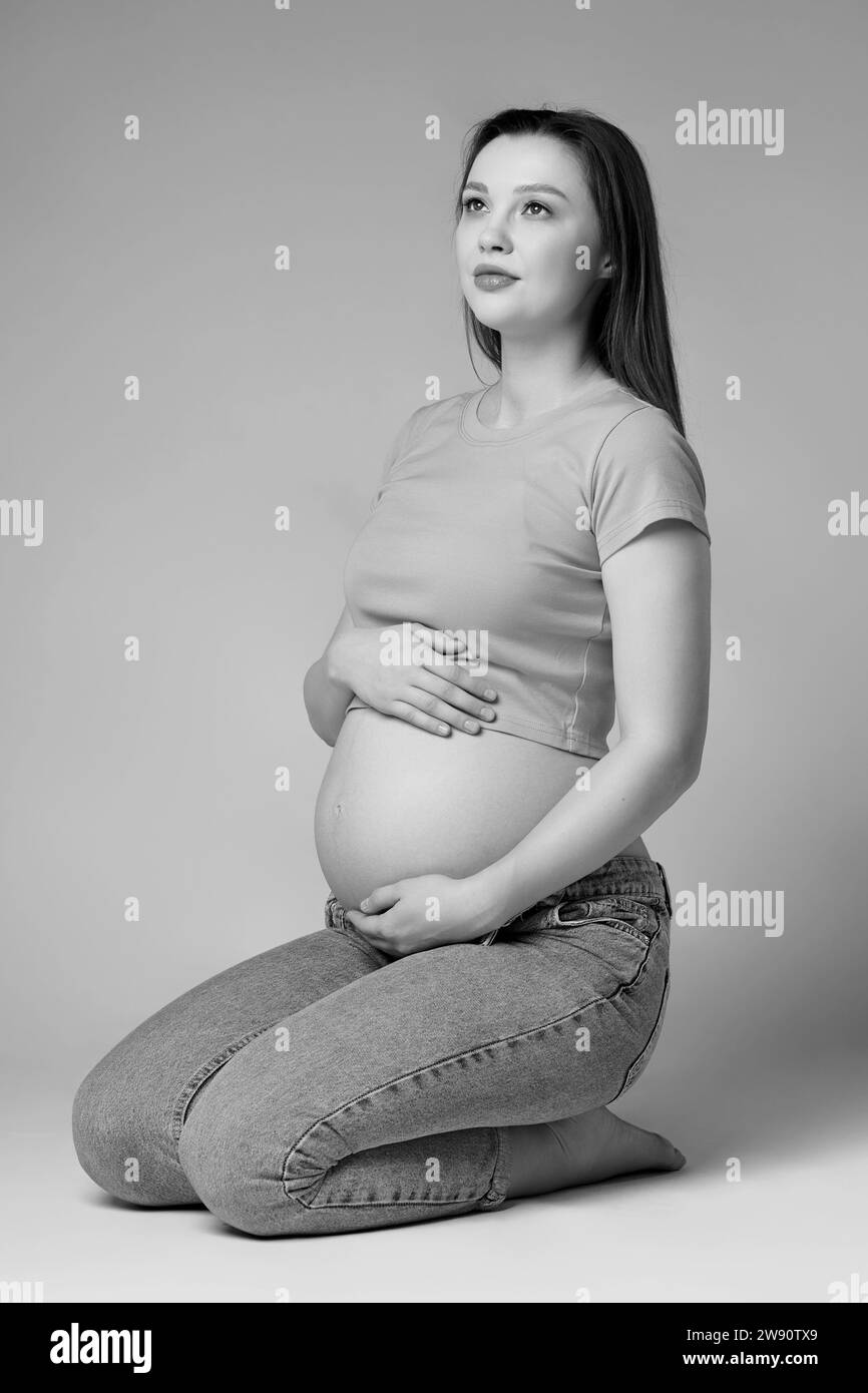 Black and white photo of young pretty pregnant woman in tshirt and