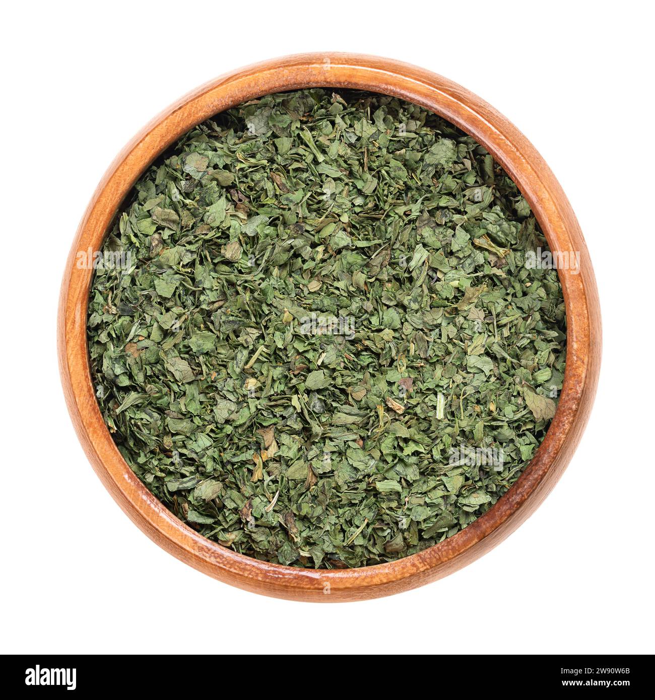 Dried cilantro leaves, in a wooden bowl. Coriander leaves, an annual herb in the family Apiaceae, used in cooking, with a tart, lemon taste. Stock Photo