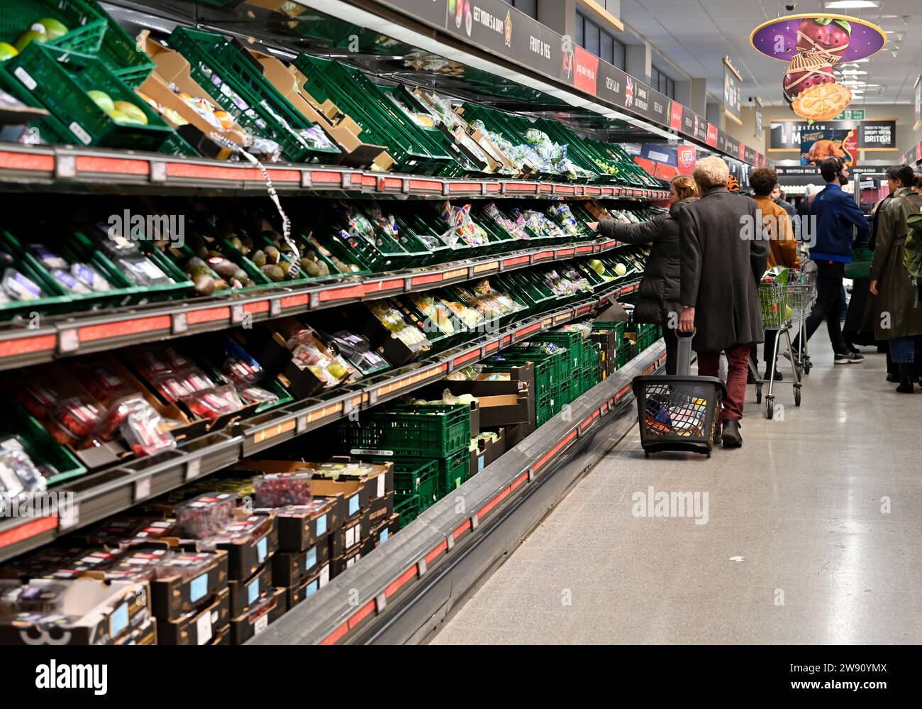 Supermarket vegetables aisle with shoppers Stock Photo