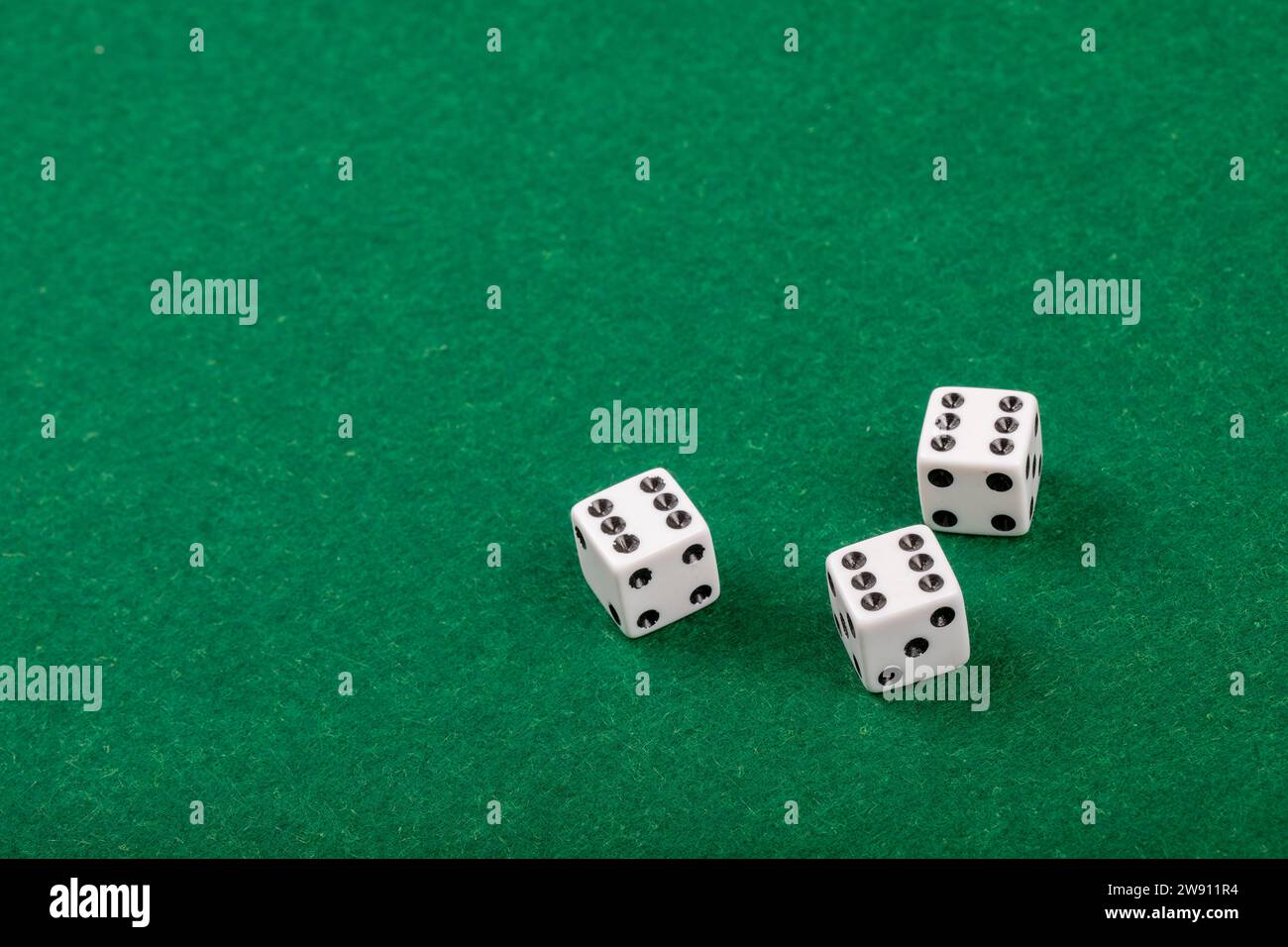 Three White Dice on Green Velvet Casino Table for Gaming and Gambling Stock Photo