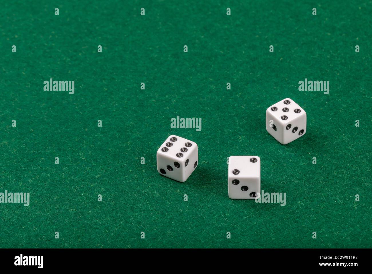 Three White Dice on Green Velvet Casino Table for Gaming and Gambling Stock Photo