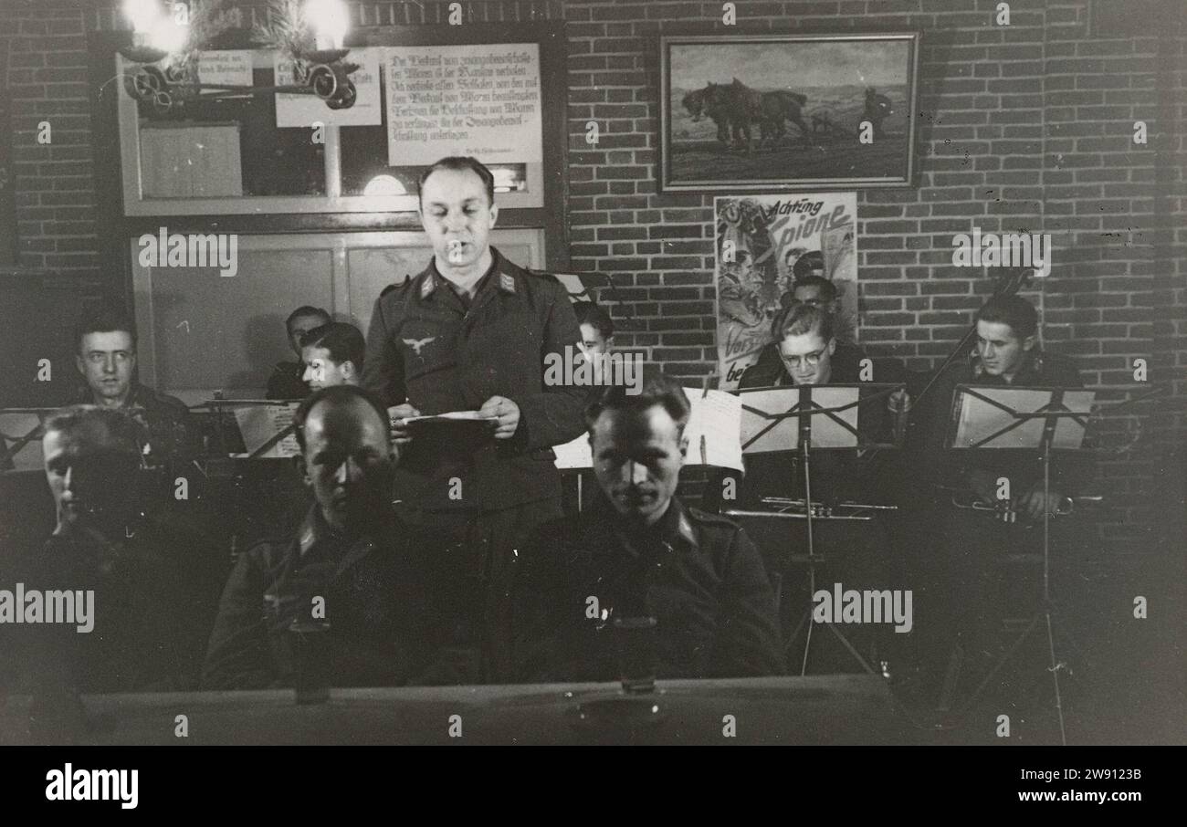 Orchestra of the Luftwaffe, 1941 - 1942 photograph Luftwaffe soldiers play music, on bladder and string instruments. For them a standard with music. To sing a state. On the wall a plate of a plowing farmer and a poster: Achtung Spione. Netherlands photographic support gelatin silver print occupation  war. military band Netherlands Stock Photo