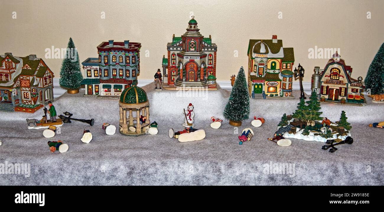 Christmas village, lighted, ceramic, little people knocked down by cat, holiday, festive, humorous, PR Stock Photo