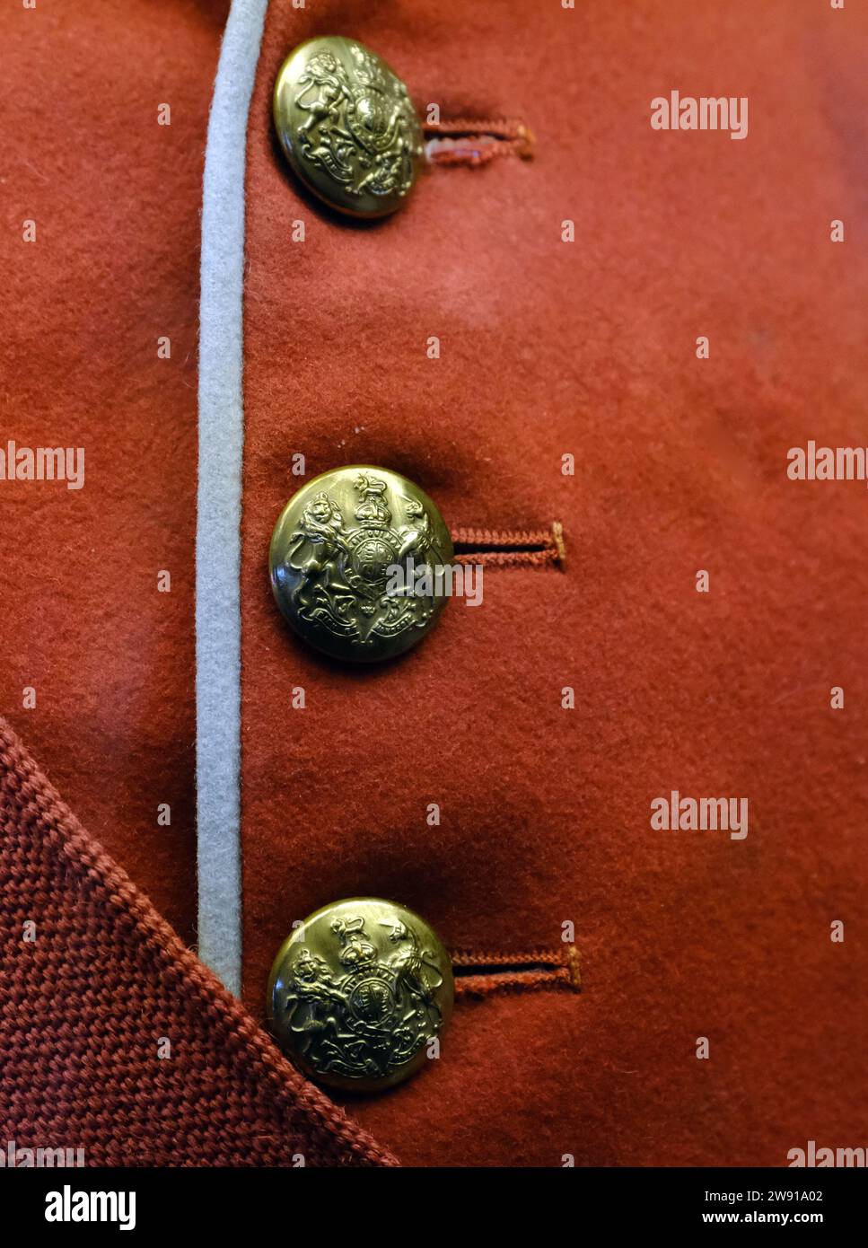 Military brass buttons on red uniform jacket. Stock Photo