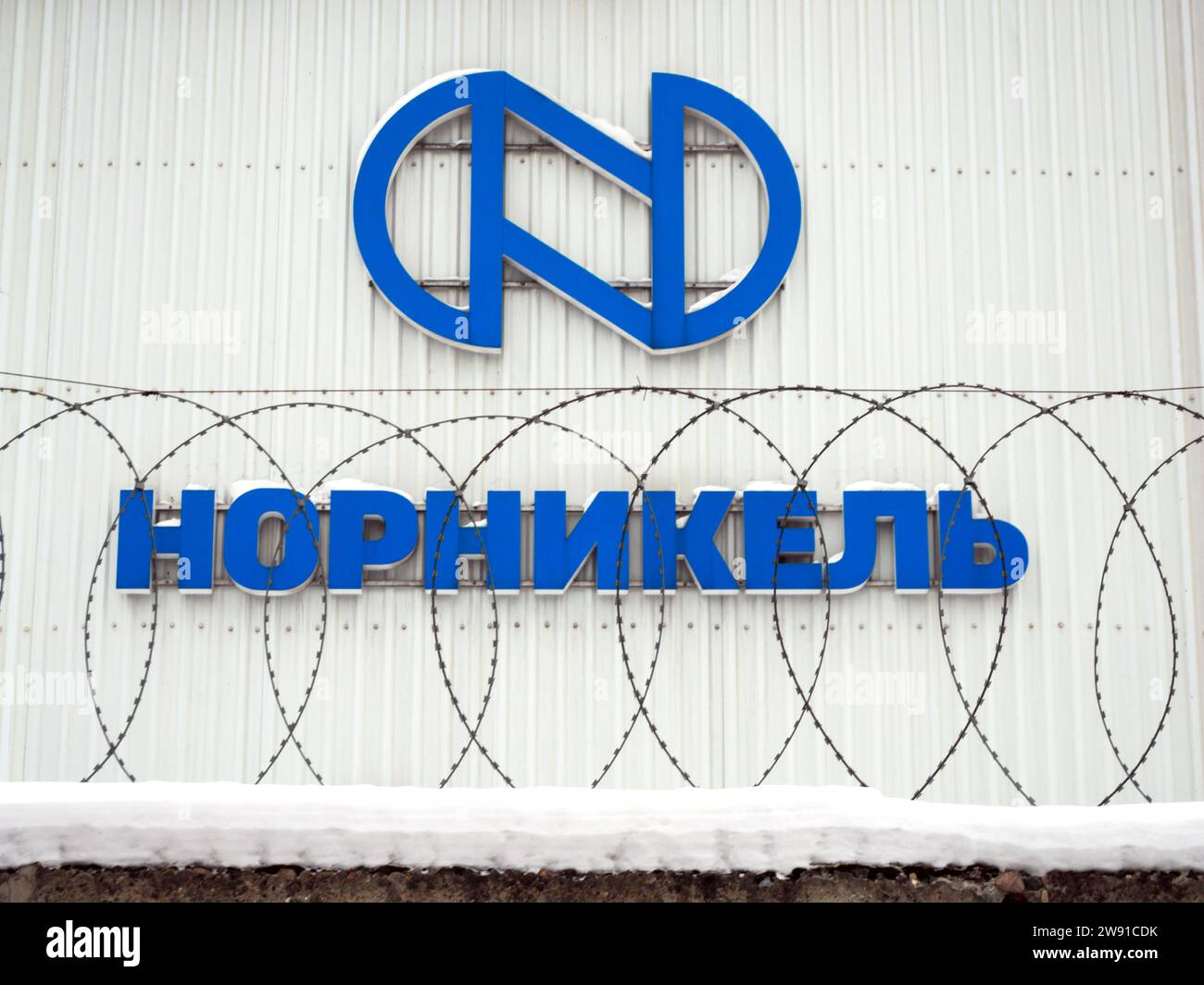 Voronezh, Russia - February 27, 2022: Norilsk Nickel company logo behind a fence with barbed wire Stock Photo