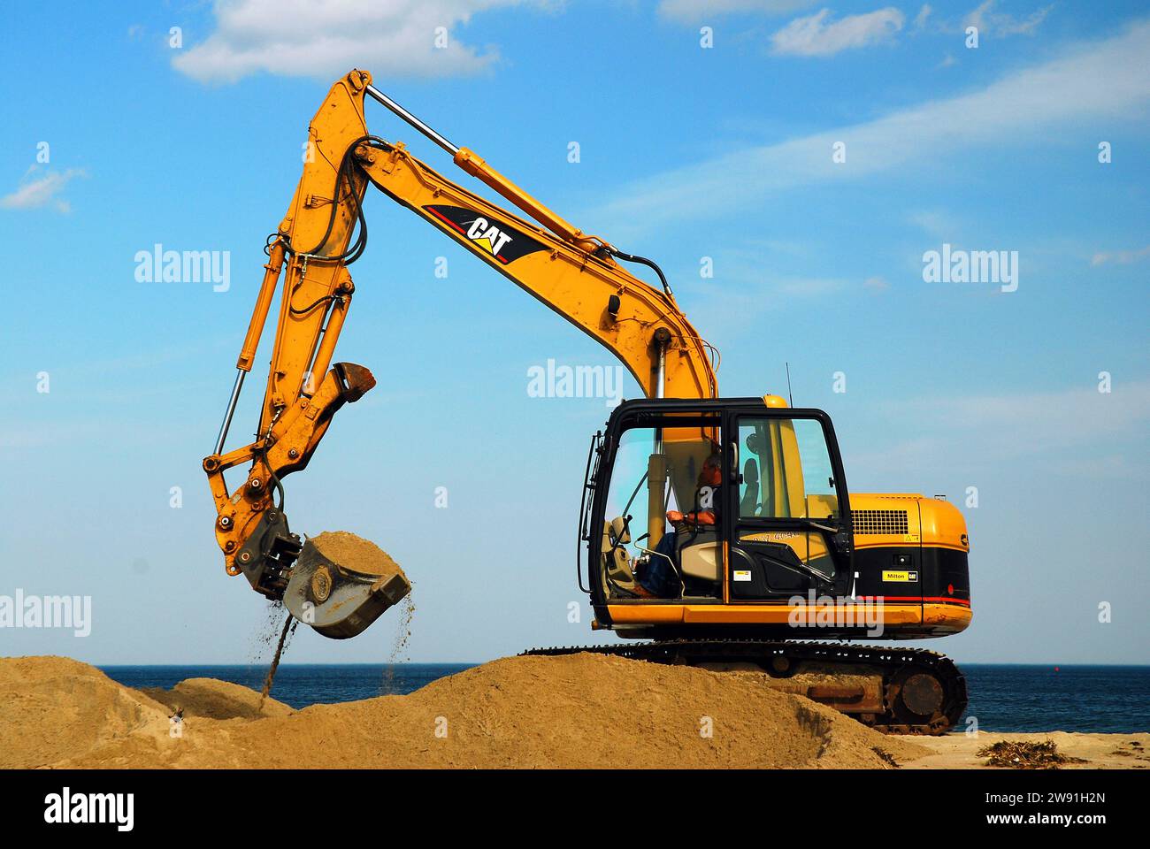 A worker operates heavy machinery is employed to repair beach erosion