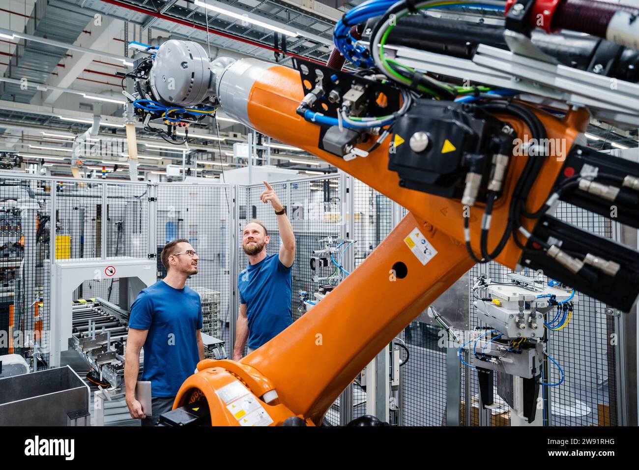 Two technicians examining industrial robot in a factory Stock Photo