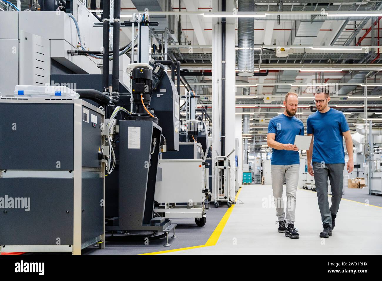 Two colleagues with digital tablet walking in a factory Stock Photo - Alamy