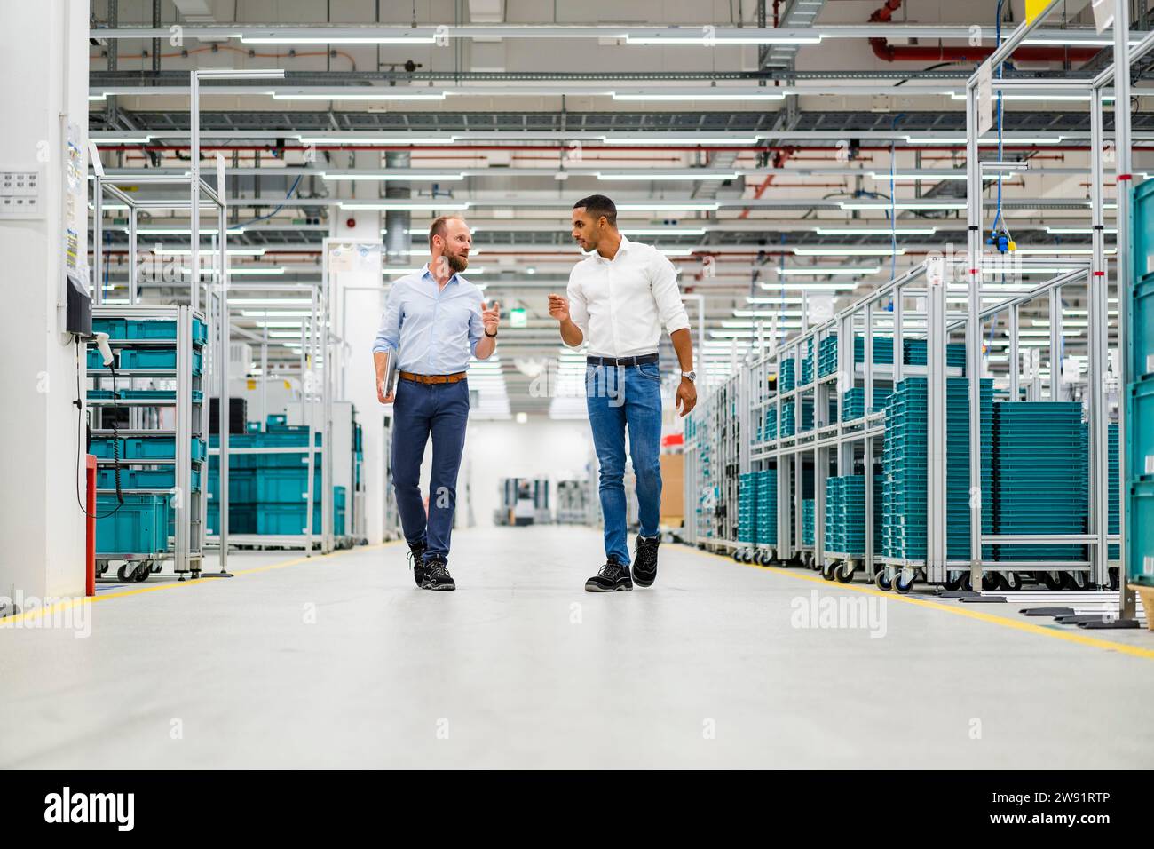Two businessmen walking and talking in a factory Stock Photo - Alamy