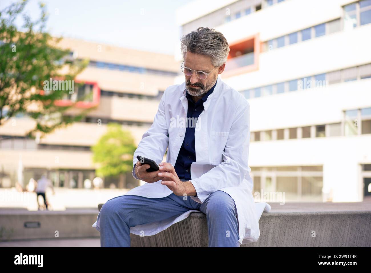 Doctor using smart phone in front of building Stock Photo