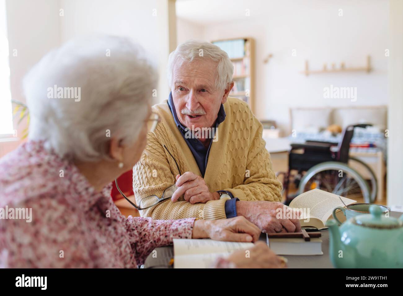 Senior man talking to woman sitting at table Stock Photo