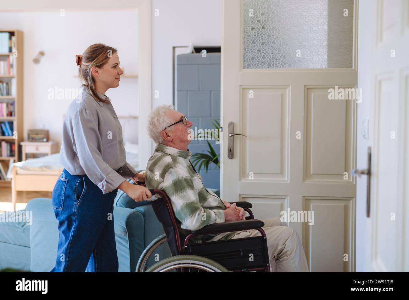 Smiling healthcare worker with man sitting in wheelchair at home Stock Photo