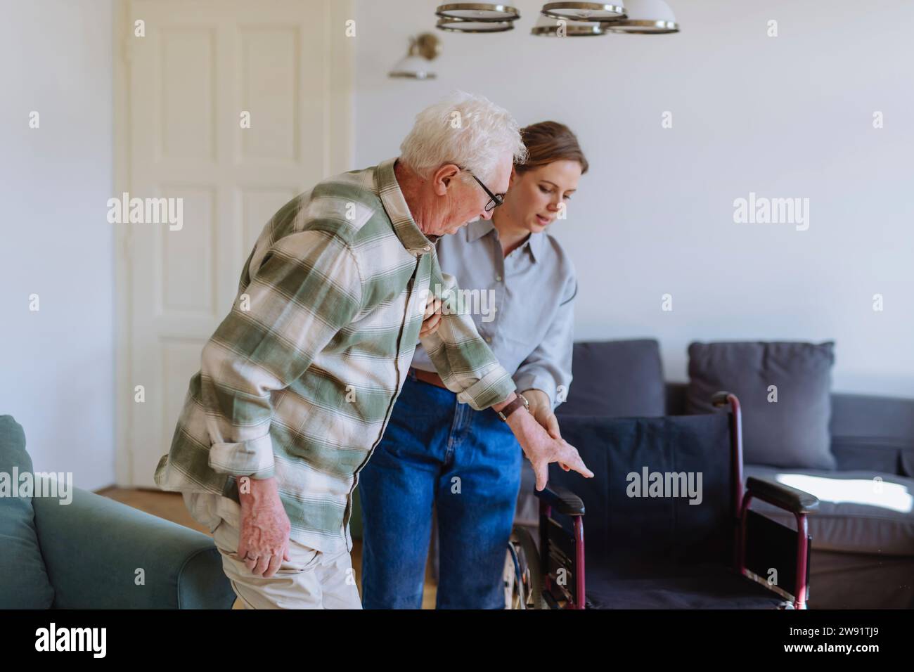 Healthcare worker holding hands and helping man at home Stock Photo