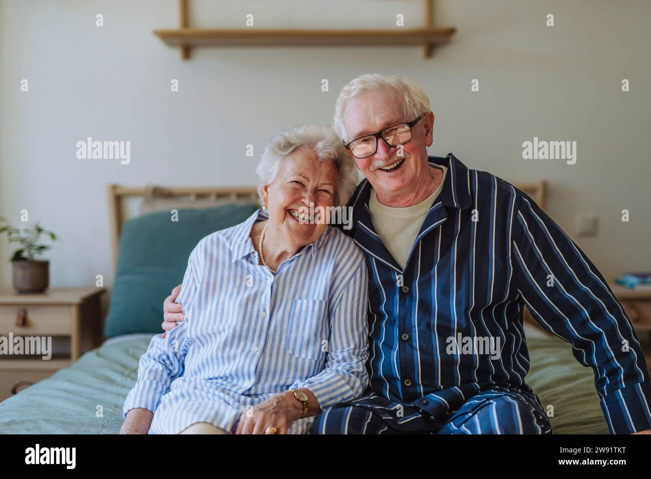 Happy senior couple sitting on bed together at home Stock Photo