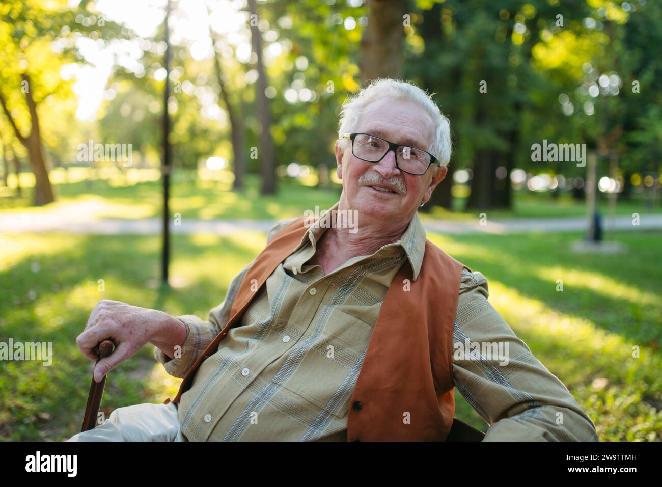 Smiling senior man sitting in park Stock Photo