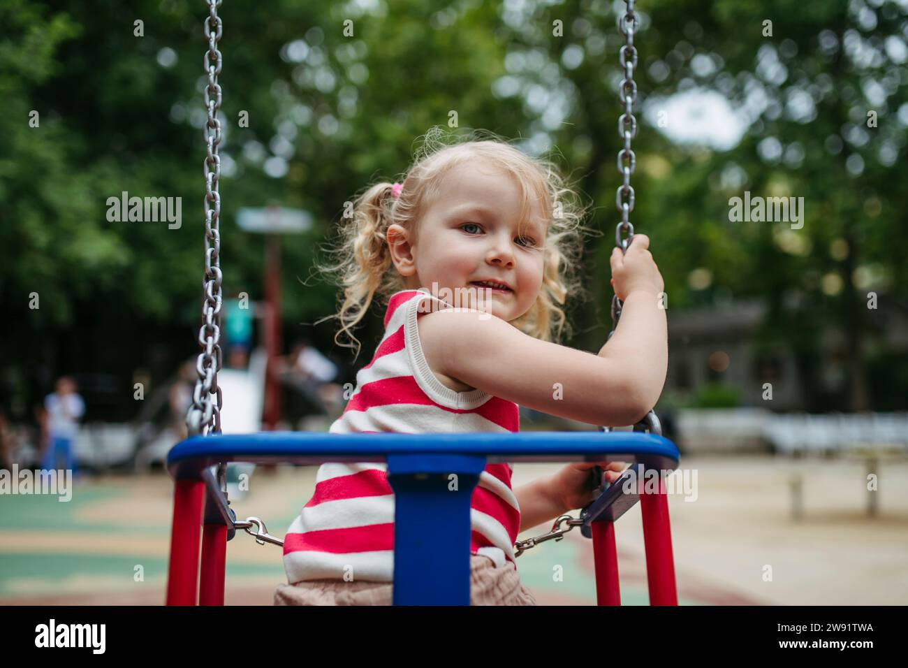 Smiling girl sitting in swing at gthe playground Stock Photo - Alamy