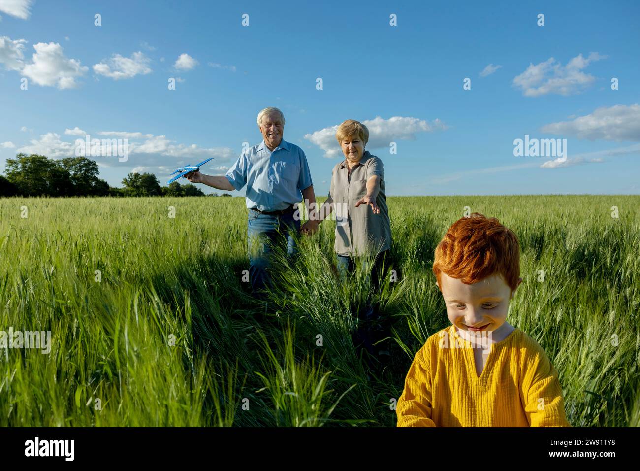 Senior couple spending leisure time with grandson in field Stock Photo