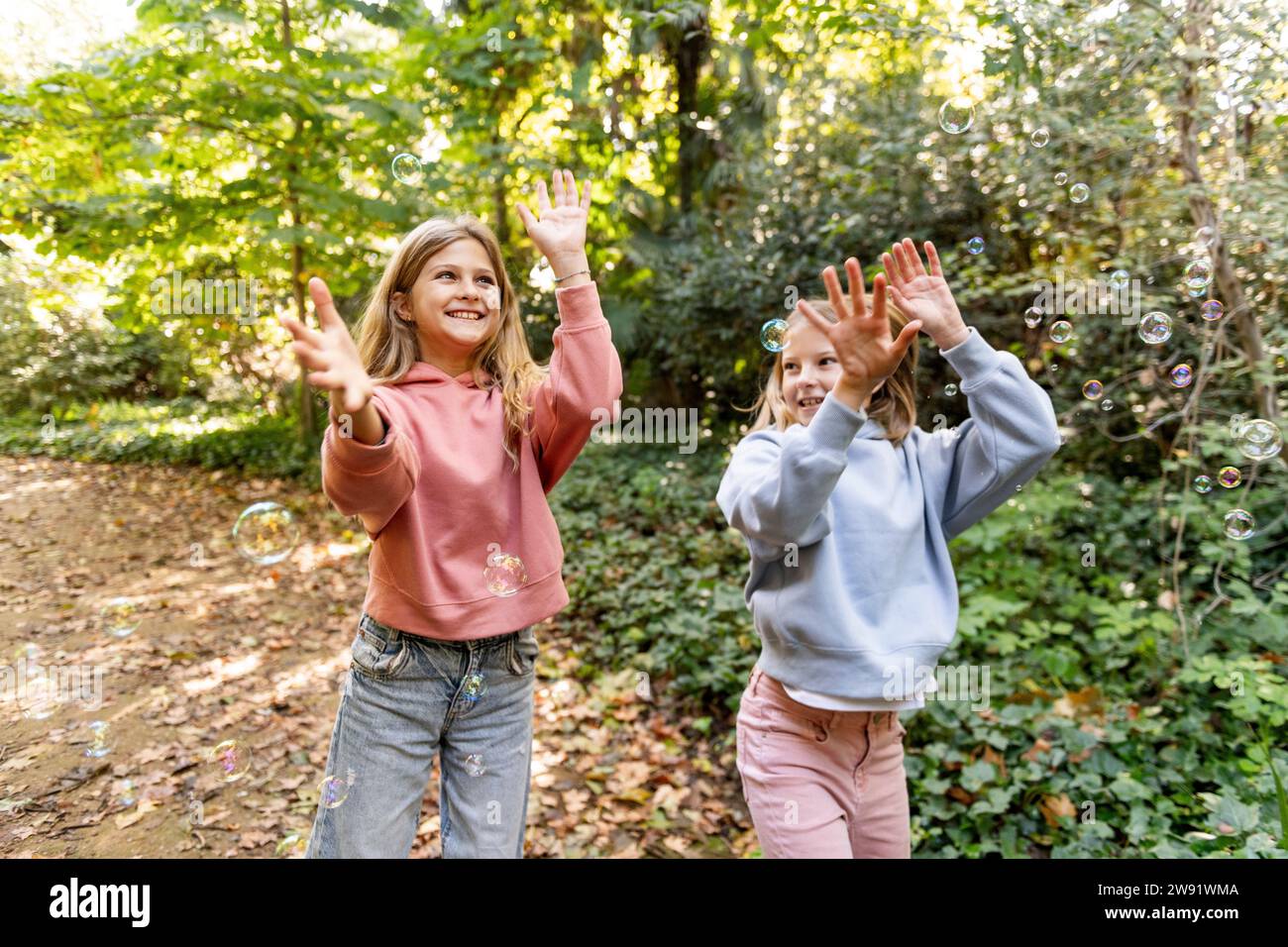 Happy girls playing with bubbles in park Stock Photo - Alamy