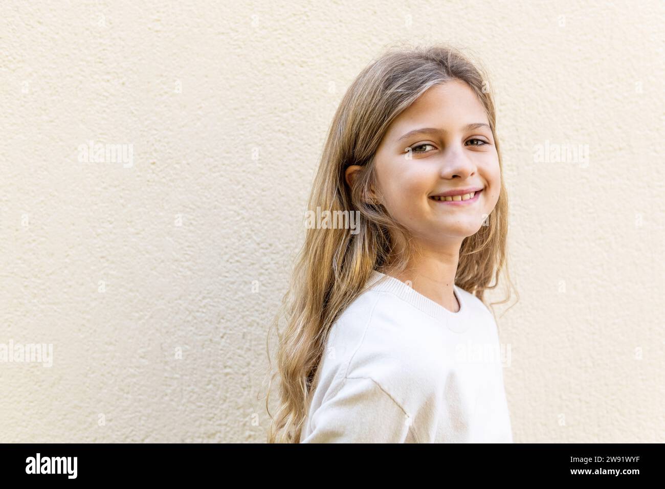 Happy girl with long hair standing in front of wall Stock Photo - Alamy