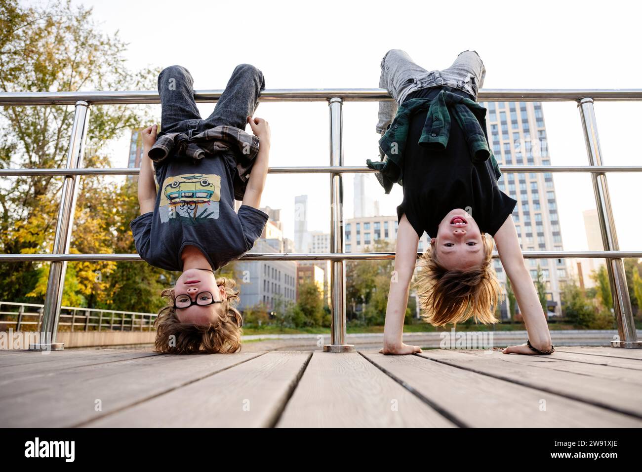 Children hanging upside down from railing Stock Photo