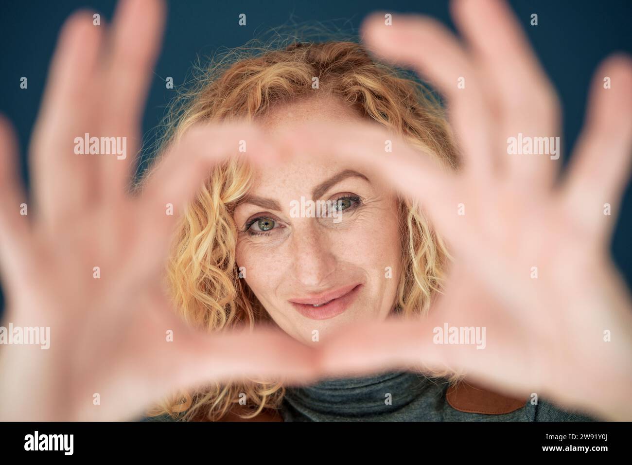 Smiling woman gesturing heart shape Stock Photo