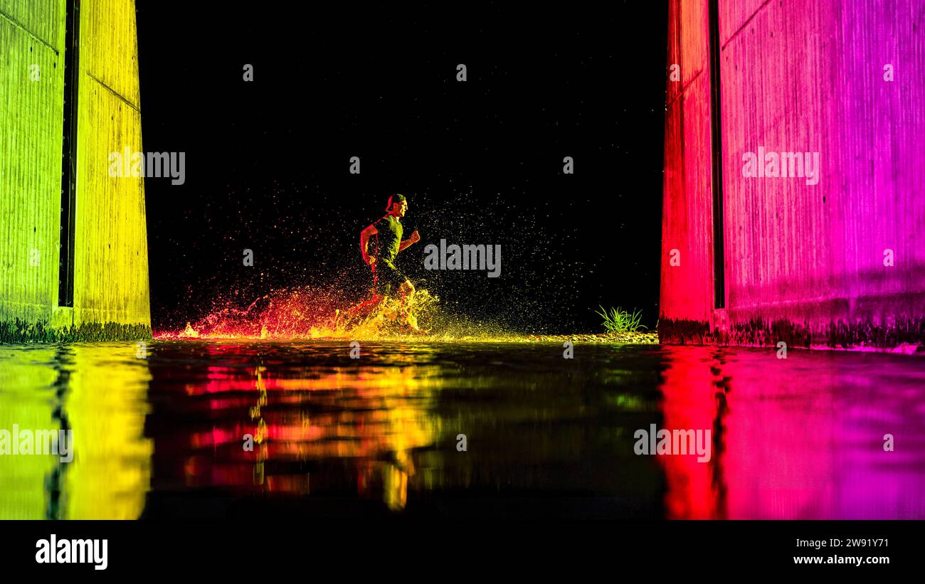 Young man running in river water with neon lights Stock Photo