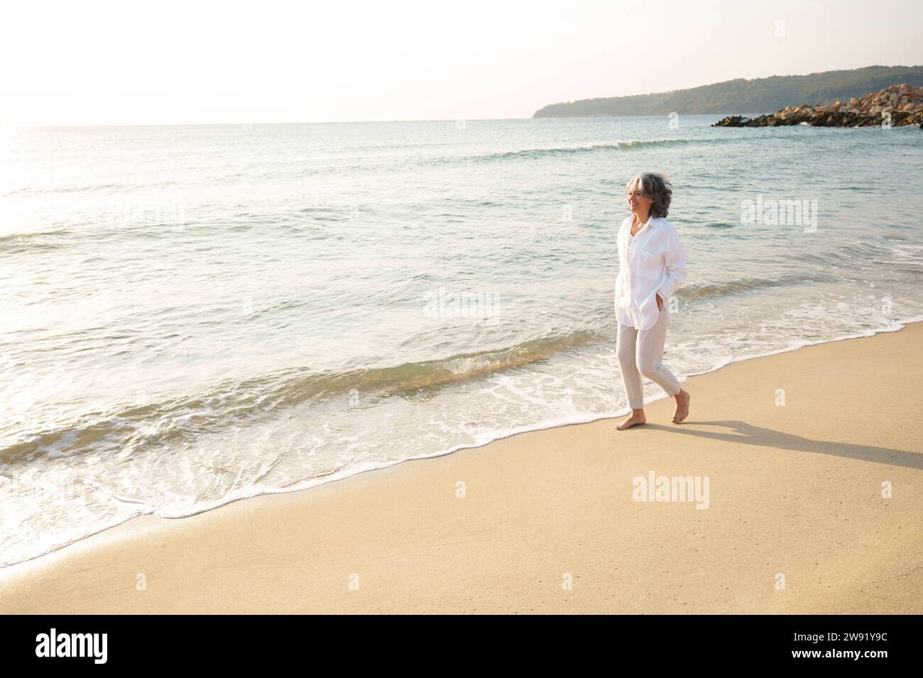 Mature woman walking on beach hi-res stock photography and images - Alamy