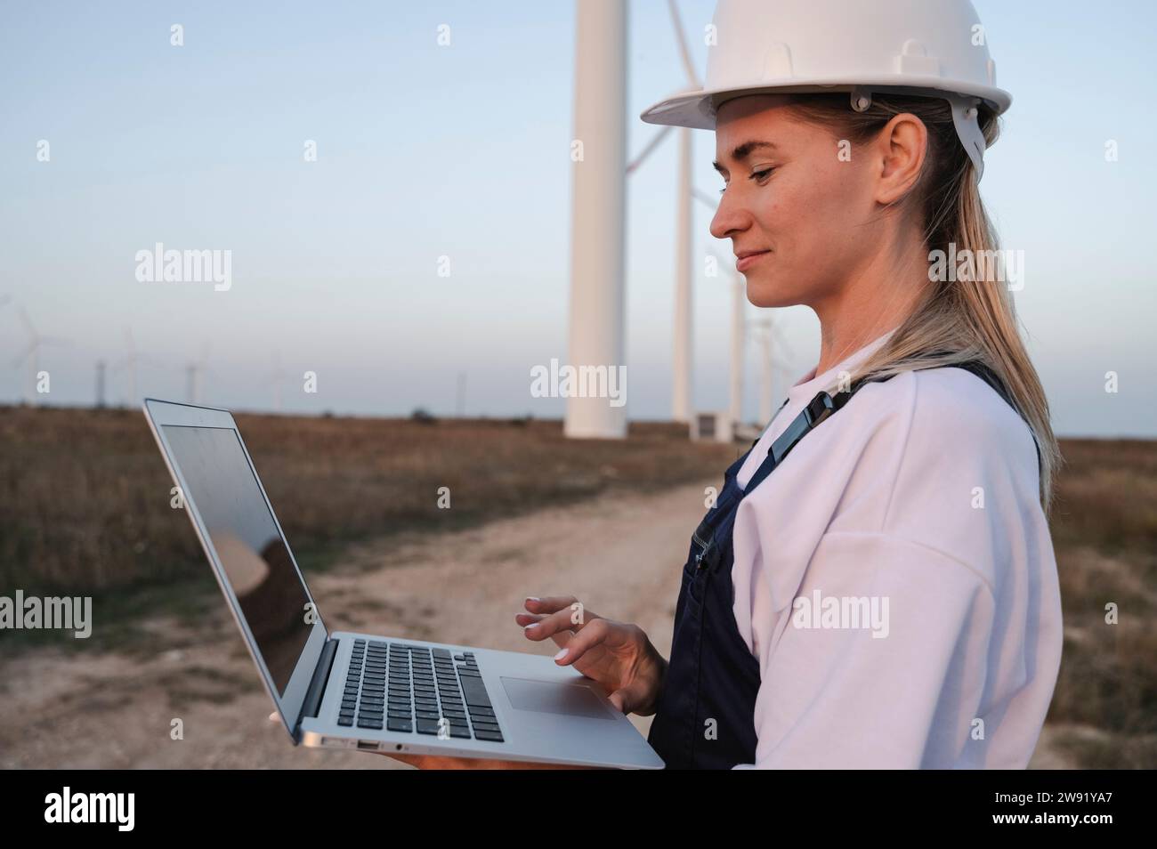Smiling engineer working on laptop at field Stock Photo
