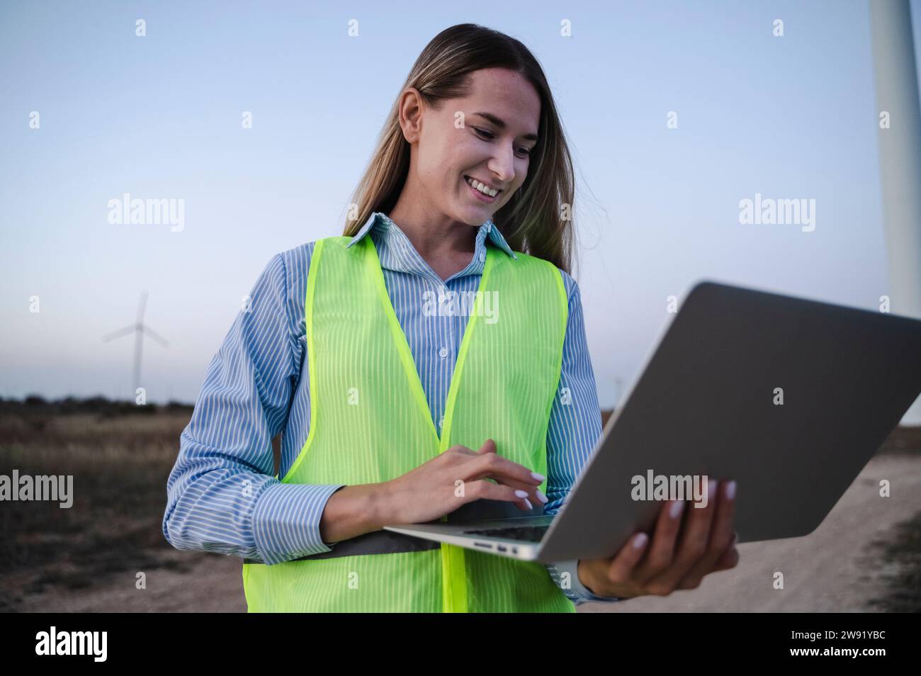 Happy engineer using laptop at field Stock Photo
