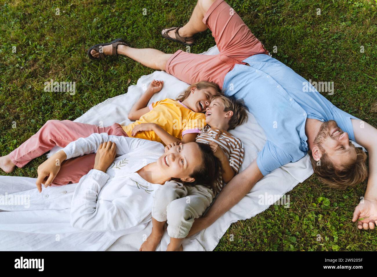 Happy family lying down on blanket at park Stock Photo - Alamy