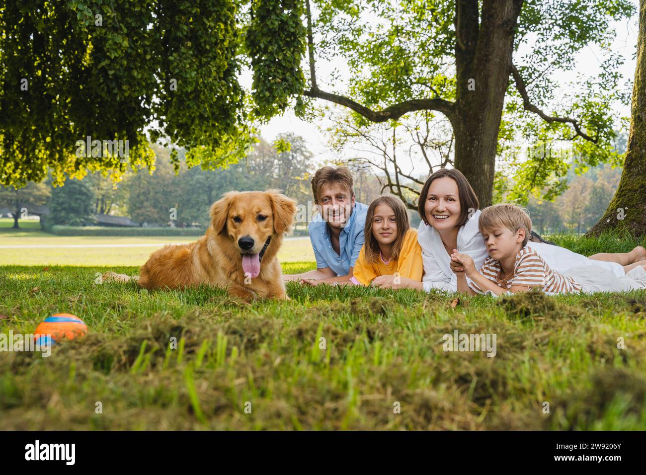 Happy family with dog lying on grass at park Stock Photo