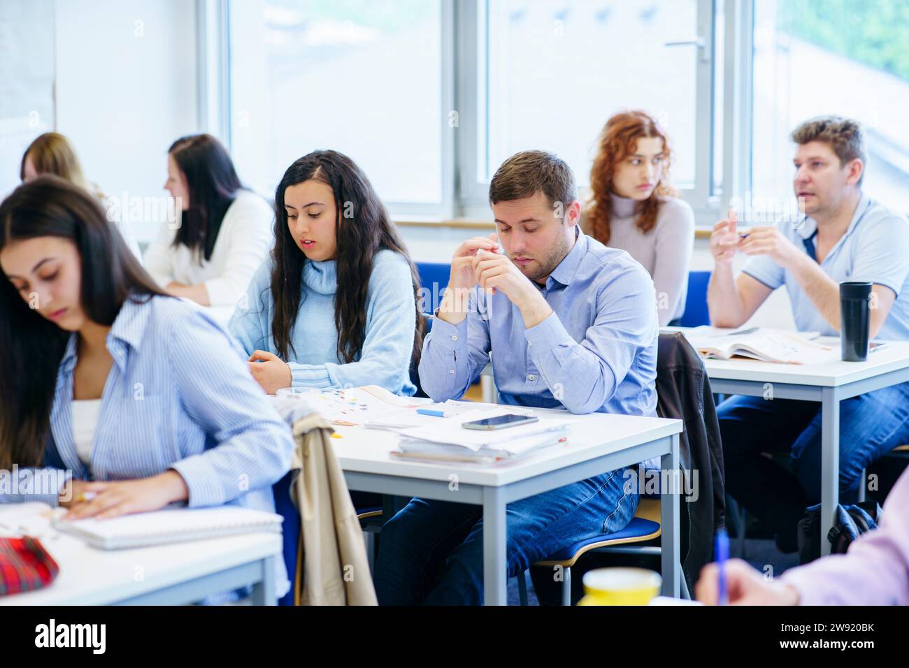 Multi-ethnic students studying at desk in classroom Stock Photo